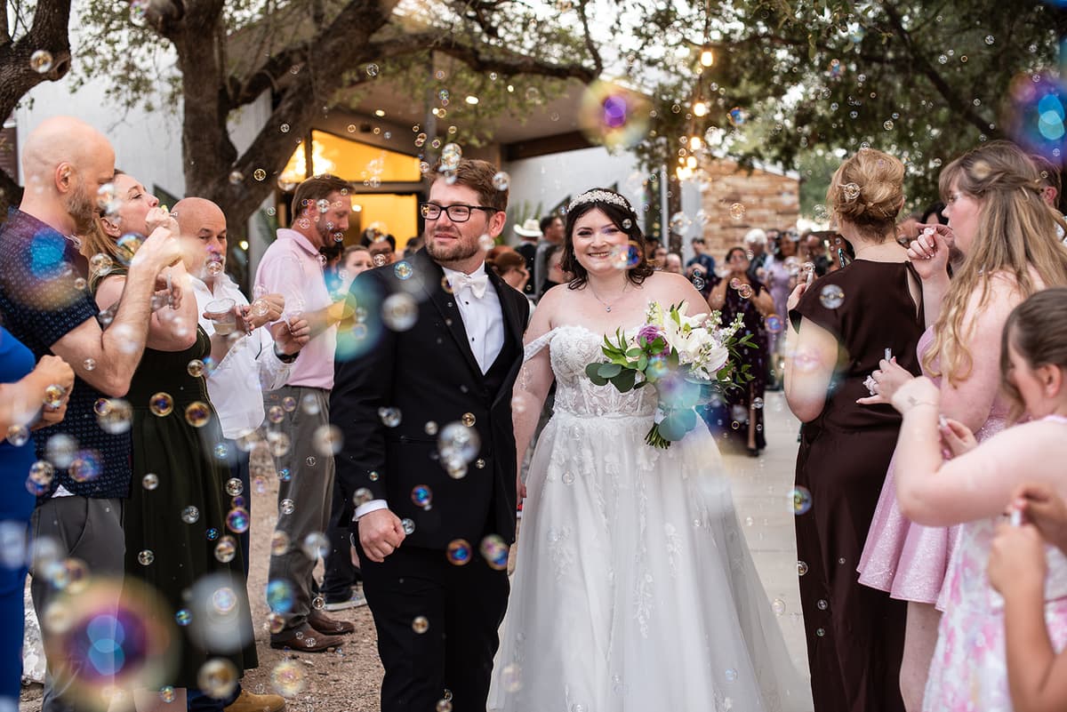 Nicole and Dylan walk through bubbles after their wedding ceremony