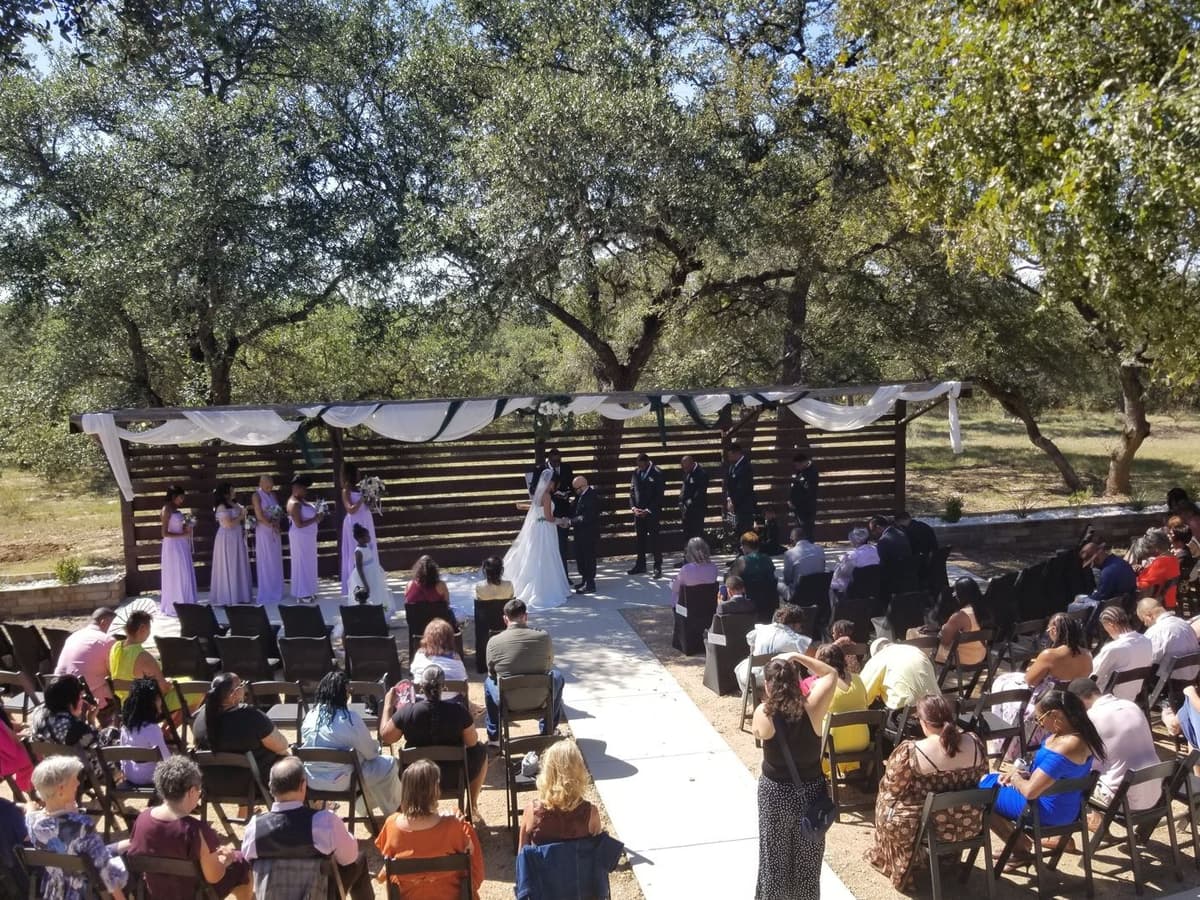 Guests watch Scott and Kimberlyn's outdoor wedding ceremony beneath Hill Country oaks