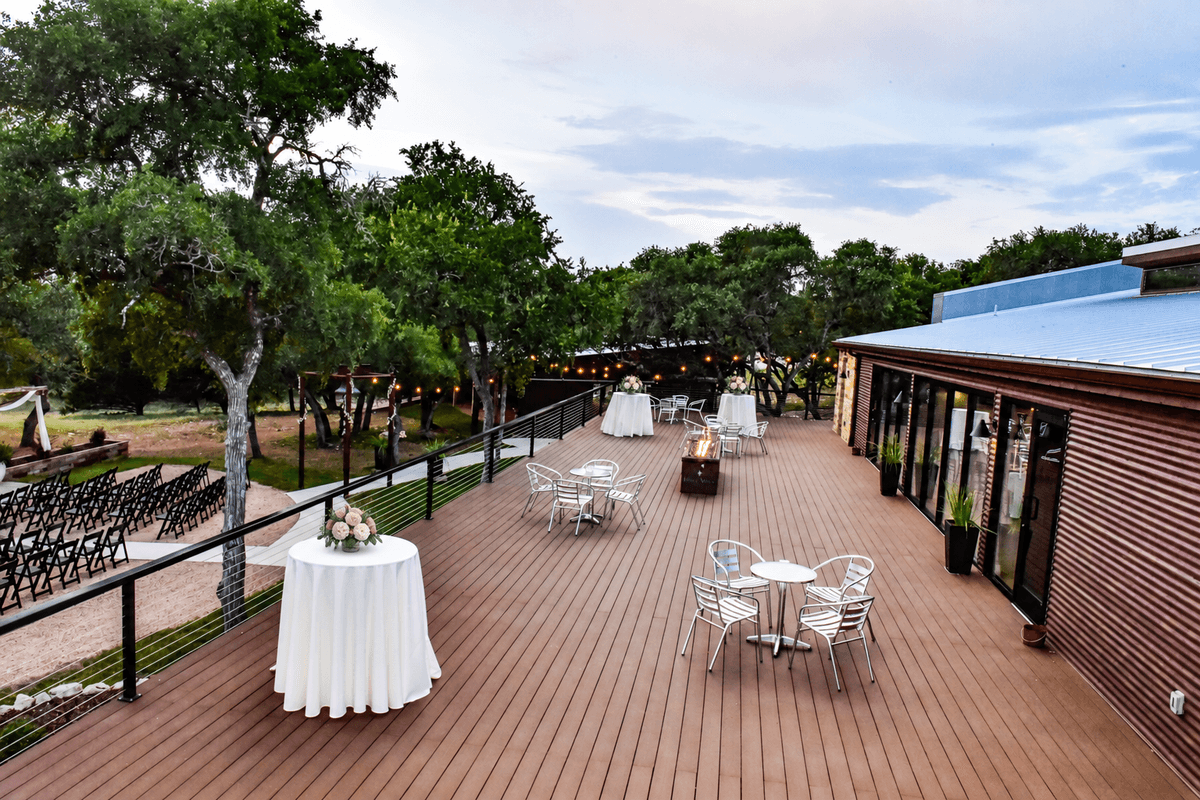 Prima Vista's deck arranged for cocktail hour with floral tables, guest seating, and warm evening lights
